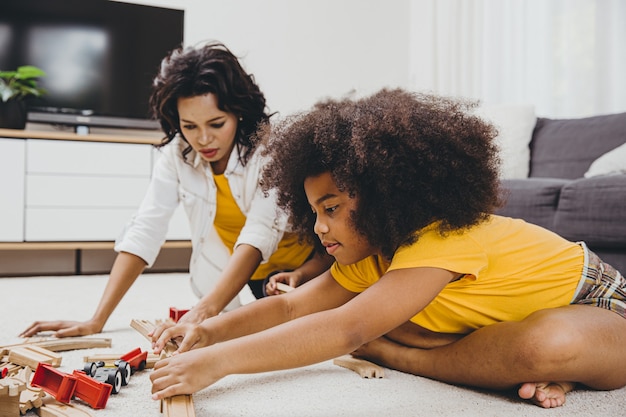 Single mom living with two daughter learning and playing puzzle toy in home apartment. Nanny looking or childcare at living room black people.