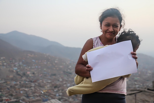 Single mother composition. A mother and her baby holding a blank sheet of paper to insert text