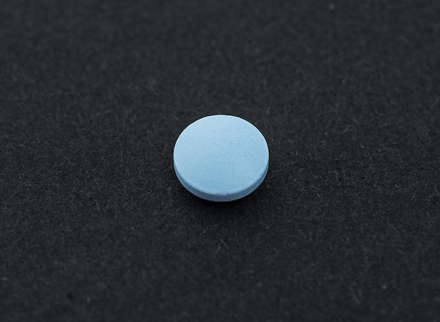 Фото Одна синяя таблетка или капсула на черном фоне вид сверху на плоскую планировку и пространство для копирования минималистическая абстрактная концепция медицины