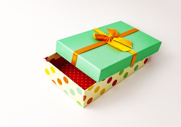 Single polka dot gift paper cardboard box with green cover and bow on white . Holiday present concept. Close up view. Selective soft focus. Text copy space.