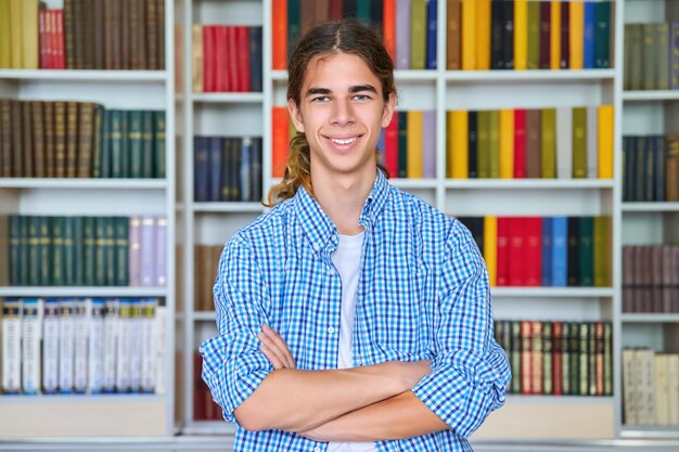 Single portrait of smiling confident male student teenager looking at camera in library