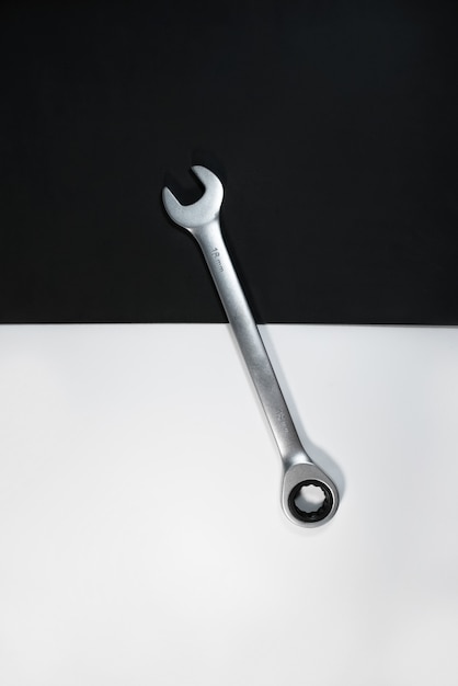 Single steel gray combination wrenches for repair on black and white background. Top view, vertical photo