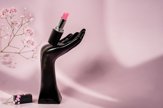 Single tube of pink lipstick on pink background with flowers