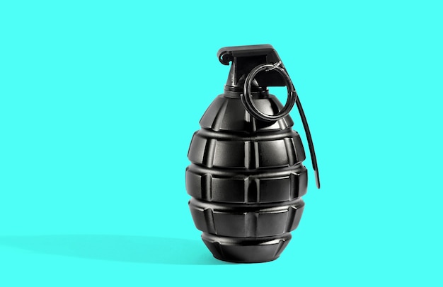 Photo single unexploded black metal grenade with round pin over cyan background with long shadow and copy space