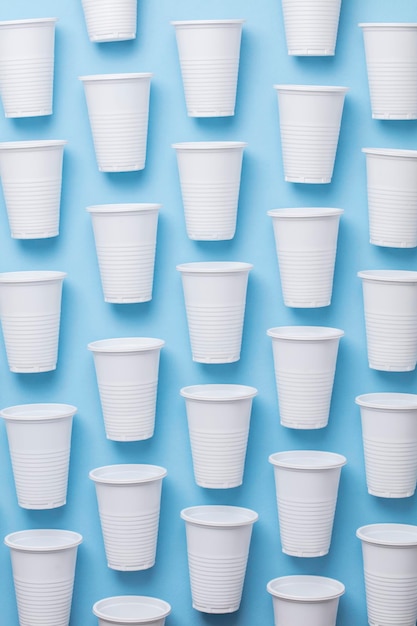 Одноразовые белые пластиковые стаканчики на синем фоне