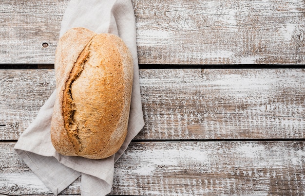 Single white bread on cloth with wooden background