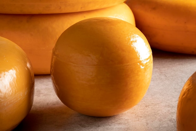 Single whole Edam cheese close up between other cheeses