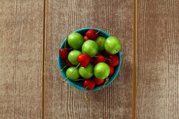 Single whole fresh green Can Erik plum and cherry close up isolated on dark background
