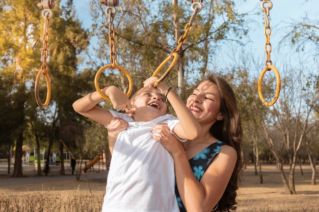 Single young mother plays with her son in the park at sunset