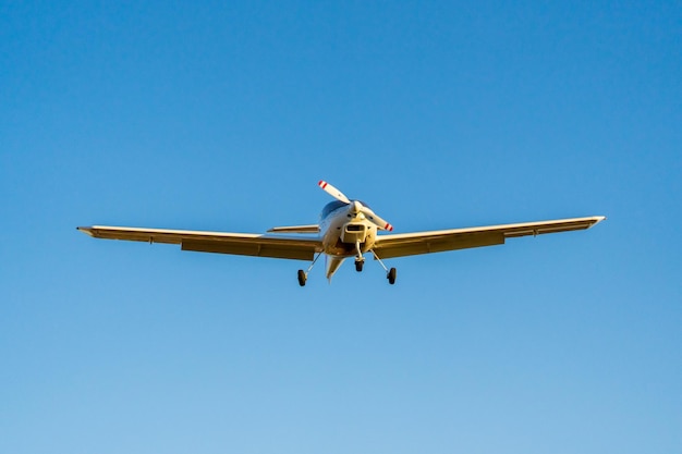 Singlepropeller vliegtuig landing van een vooraanzicht in een blauwe lucht