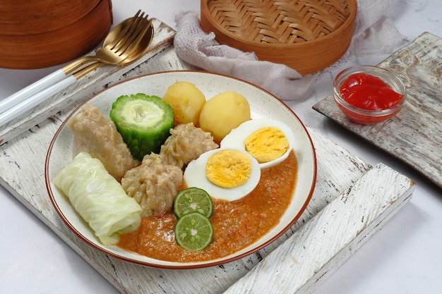 siomay または somai と呼ばれるインドネシアの魚の蒸し餃子と野菜のピーナッツ ソース添え。