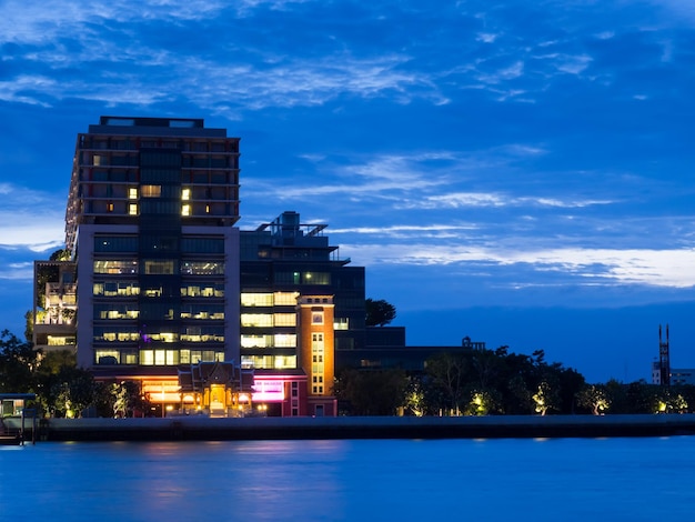 Photo siriraj hospital buidlings along chao phraya river in bangkok under sunset twilight cloudy sky in evening thailand