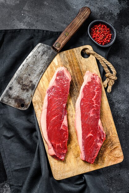 Sirloin steak on a cutting Board. Organic beef meat. Black surface. Top view