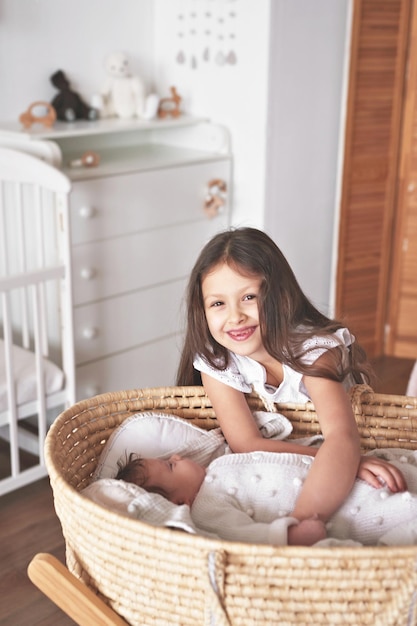 Sister and brother Girl with baby boy in wicker cradle Happy childhood Children room