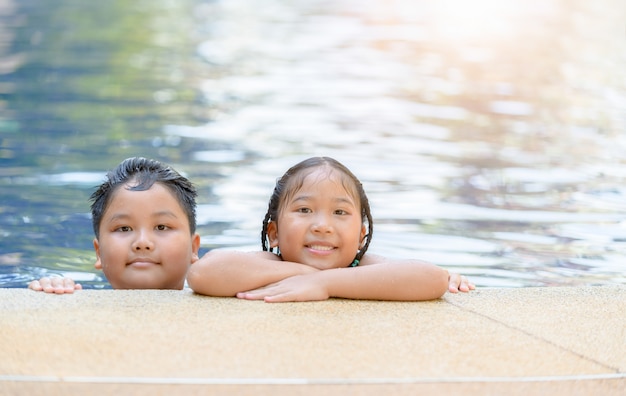 Sister and brother playing at swimming pool,