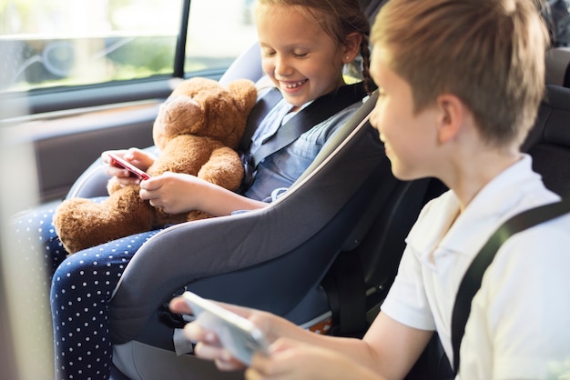 Sister and brother playing with digital devices in the car