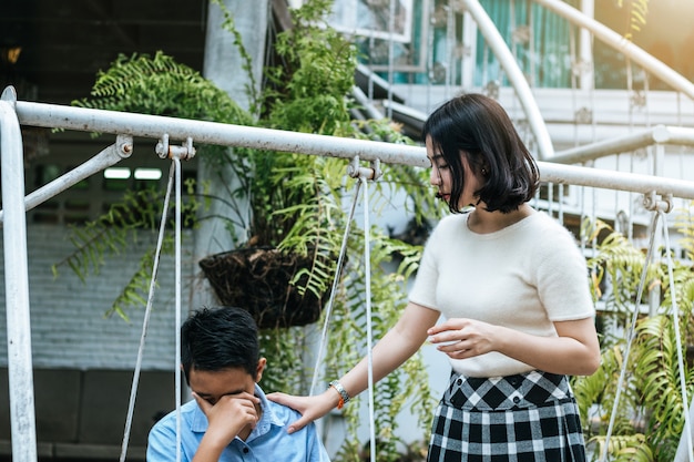 The sister comforted her brother sitting cry on the swing.