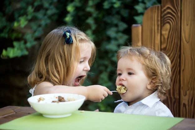 妹が男の子の女の子に餌をやるのは、弟にスプーンの子供用の食べ物を与える