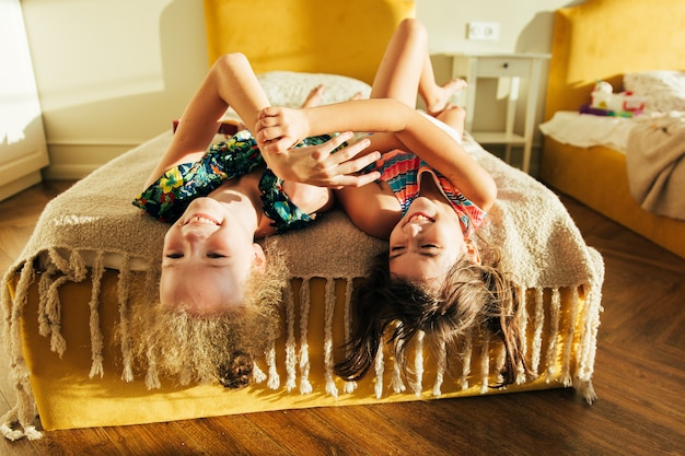 Sister having fun in the bed, and sharing moments of love. Little girls having fun together in bed. Little girls playing at home on bed.