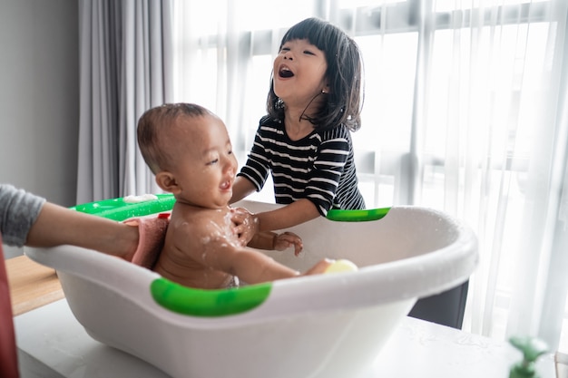 Sister help her baby brother take a bath