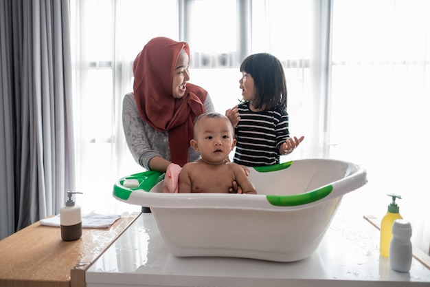 Sister help her mother to wash baby brother