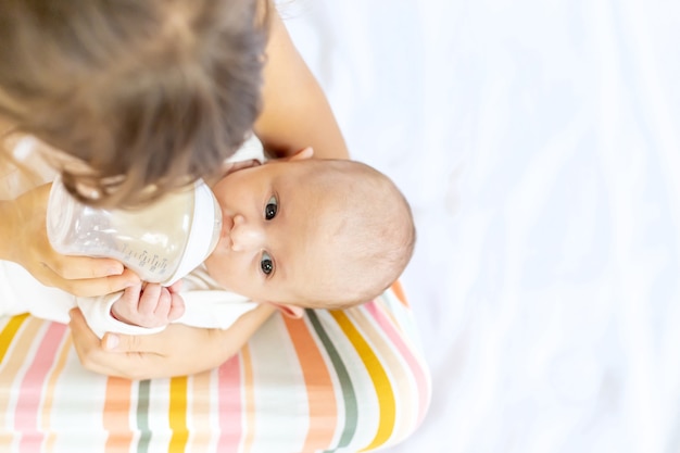 Sister is feeding a newborn baby