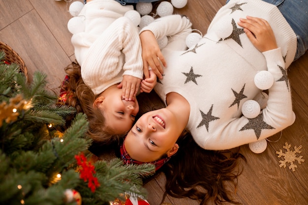 sister lie next to a Christmas tree