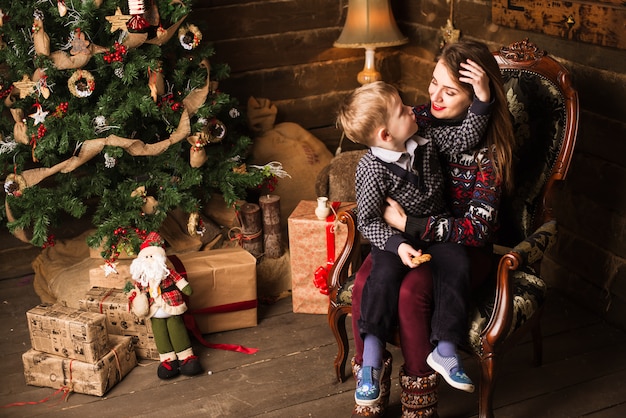 Sister and little brother sitting in front of Christmas tree