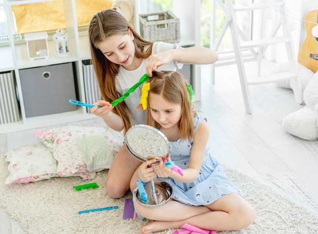 Sister making hairstyle to little girl