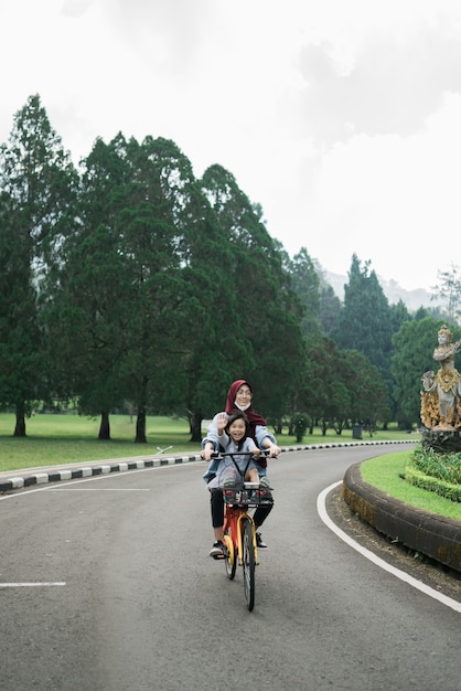 Sister takes her sibling riding a bike in the park