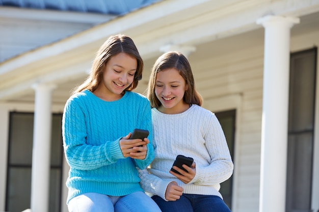 Sister twins having fun with technology smartphone