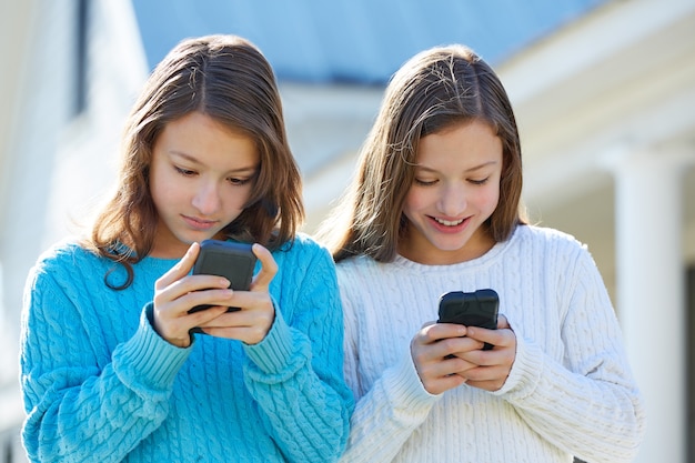 Sister twins having fun with technology smartphone