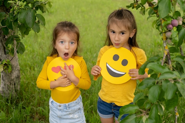 the sisters are holding the faces of happy emoticons in their hands