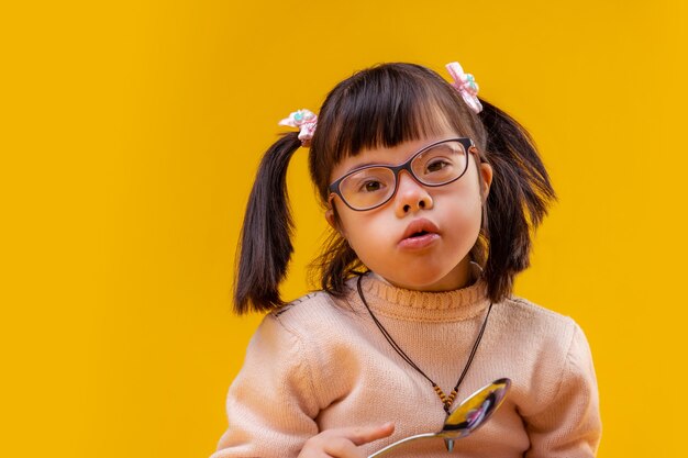 Sisters eating milk. Curious small funky girl holding big metal spoon while having meal