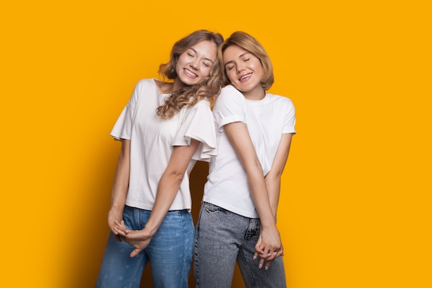 sisters gesturing happiness with closed eyes