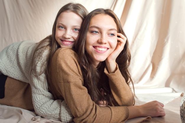 Photo sisters having fun on beige color textile background