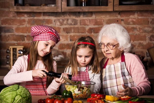 Foto le sorelle aiutano la nonna a preparare l'insalata