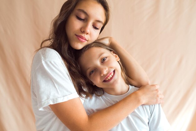 sisters hugging on beige color textile background