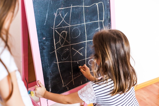Sisters older and younger girls play games on the blackboard