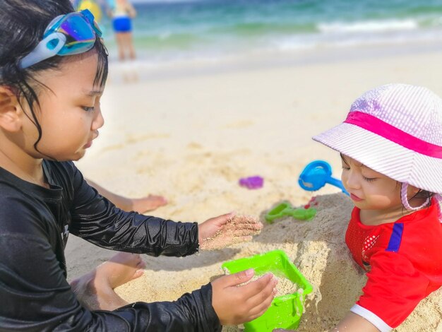 写真 ビーチで砂の上で遊ぶ姉妹