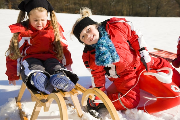 Sisters in snow on toboggan