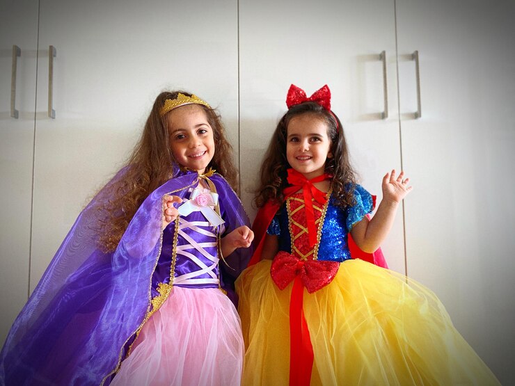 Photo sisters wearing costumes standing against cabinet