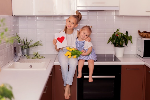 сестры с букетом цветов и открыткой на кухонном столе