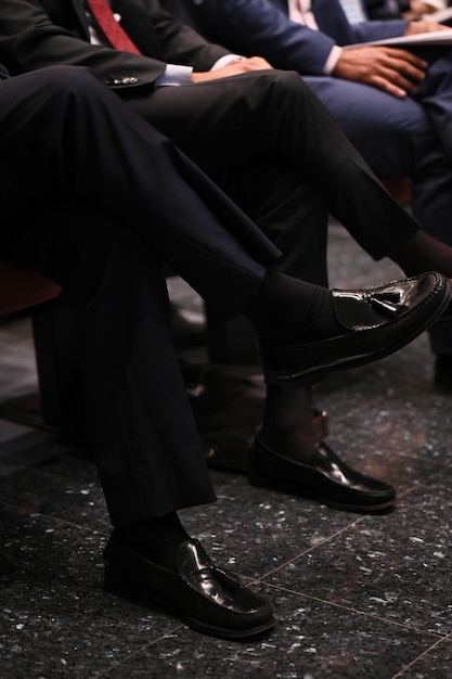 A sit man with moccasin cross his legs during a meeting