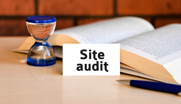 Site audit - business concept text on a white background with a hourglass and an open book