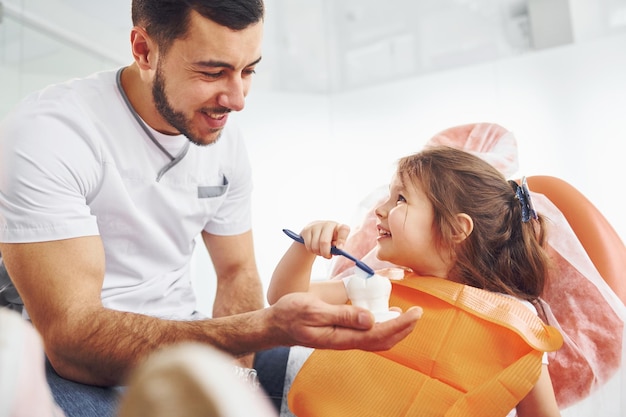 Sits on the chair Little girl visiting dentist in clinic Conception of stomatology