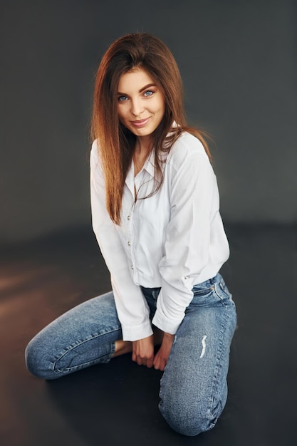 Sits on the floor Young beautiful woman is posing for the camera in the studio