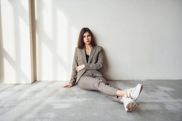 Sits on the floor Young woman in formal clothes is indoors Conception of style