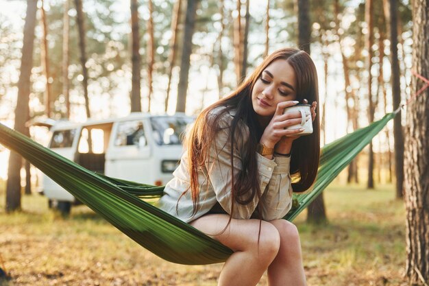 Sits on the hammock Woman is traveling alone in the forest at daytime at summer