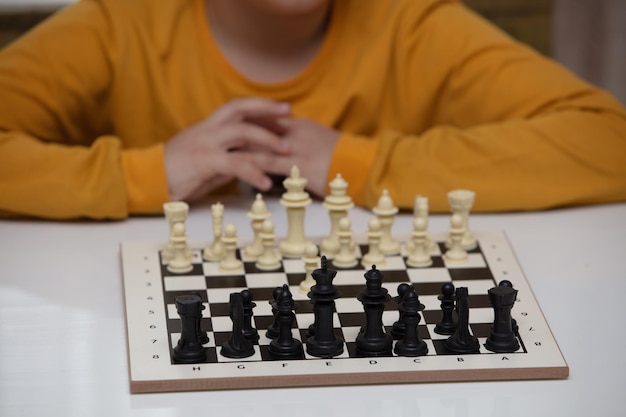 Sits at a table and plays chess the kid concentrated